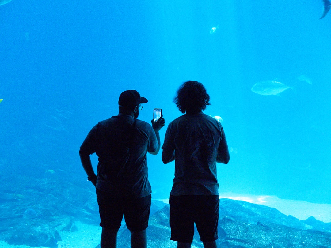 Two people taking photos at an aquarium.