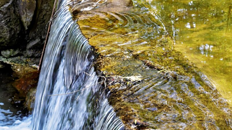 a close up of a small waterfall in a body of water